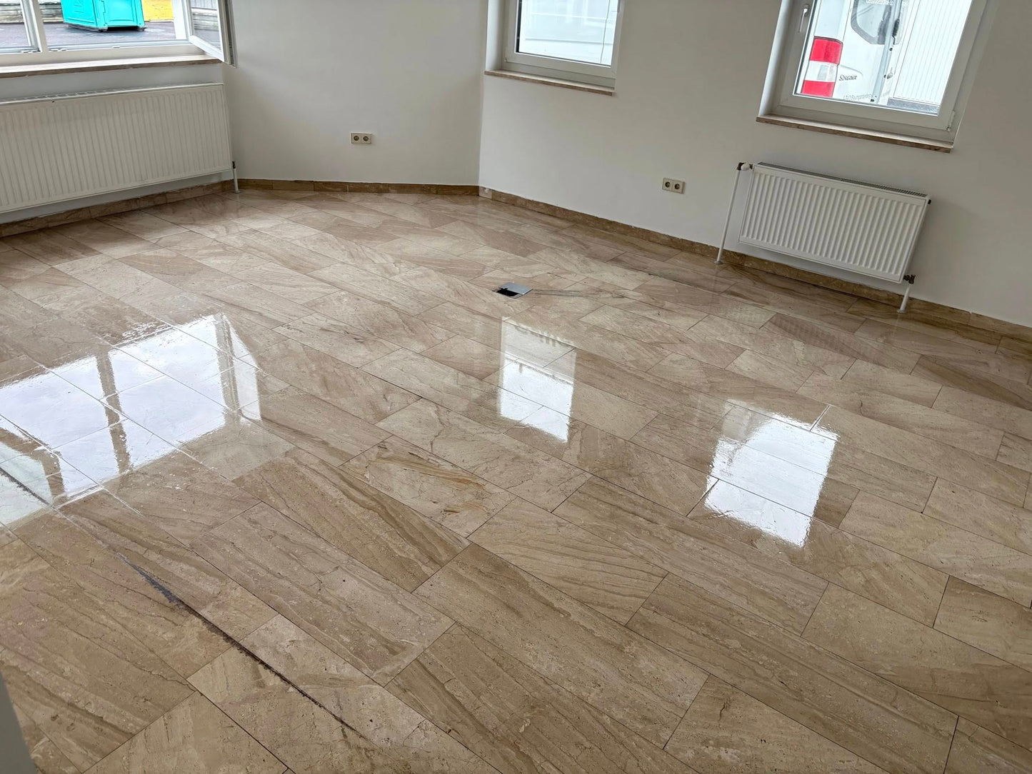 Clean, shiny marble floor in a bright, empty room with large windows and radiators